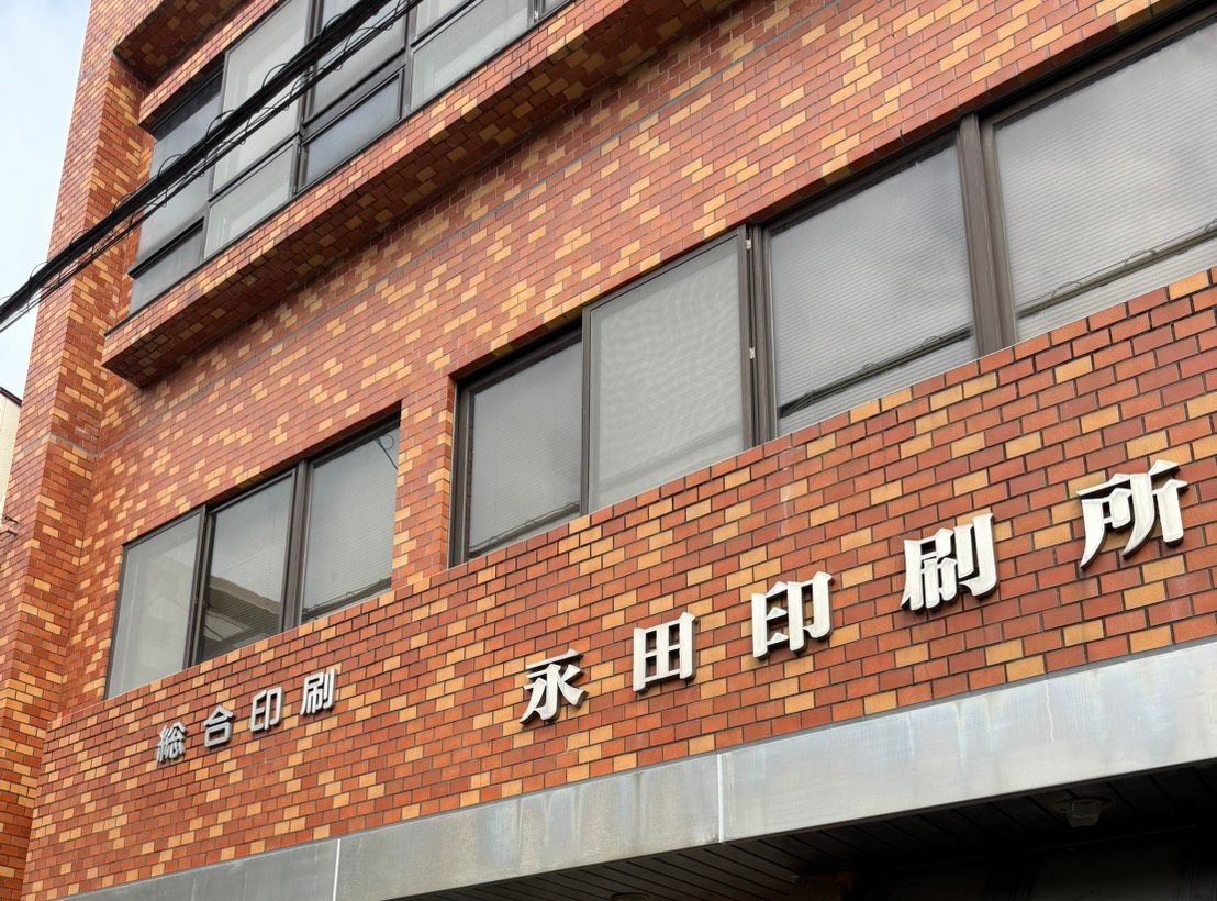 総合印刷 永田印刷所の看板と、れんが張りの社屋