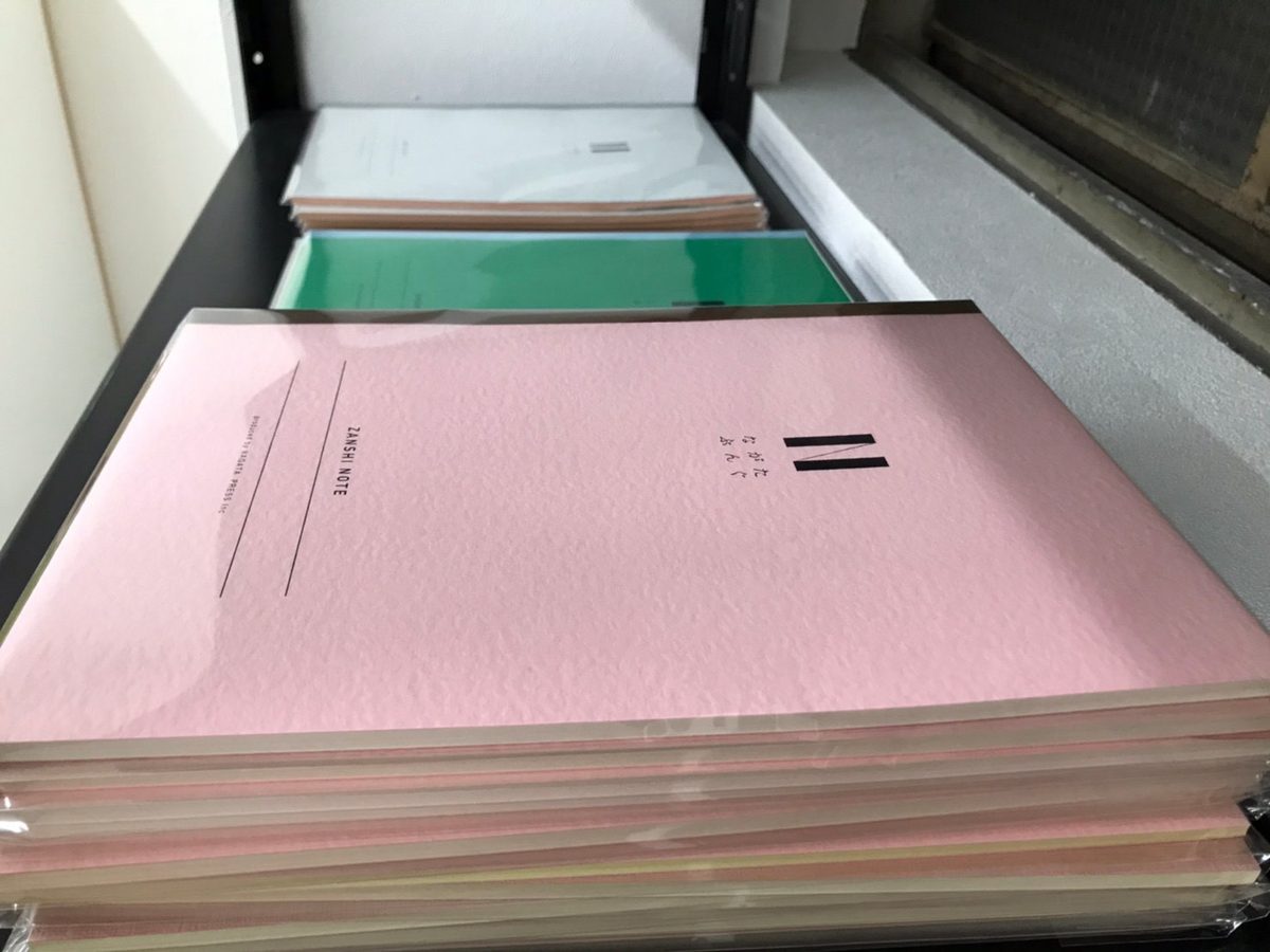 製本の台に積まれた、表紙をつけたノートの束